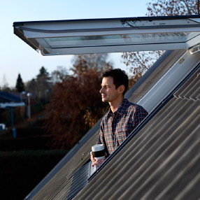 man enjoying coffee on rooftop through skylight