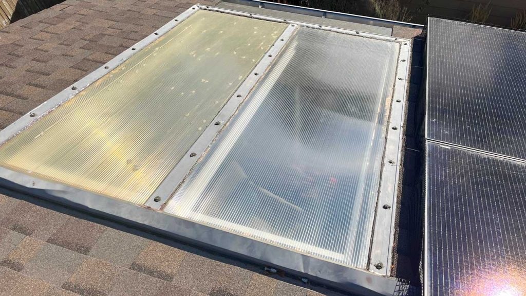 The hail damaged acrylic skylight nearly touches the solar panels.