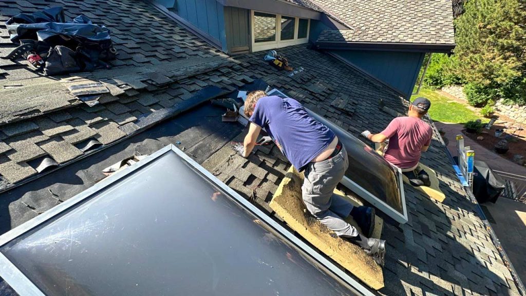 Technicians remove shingles along with the outdated dome skylights.