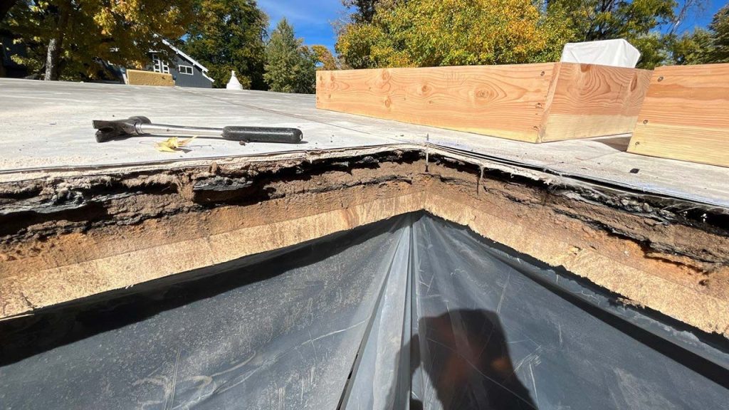 An image showing the edge of the hole cut in the roof and plastic sheeting to control dust and debris.