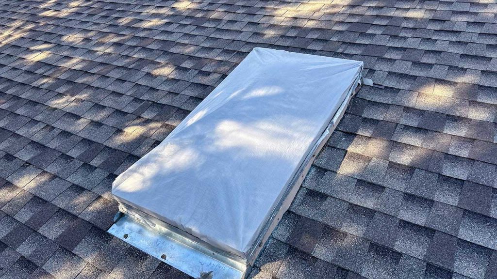 An image of a hail damaged skylight with a temporary plastic sheeting cover.