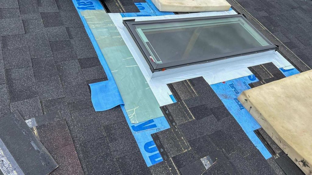 Underlayment surrounds the mounted skylight on the roof.