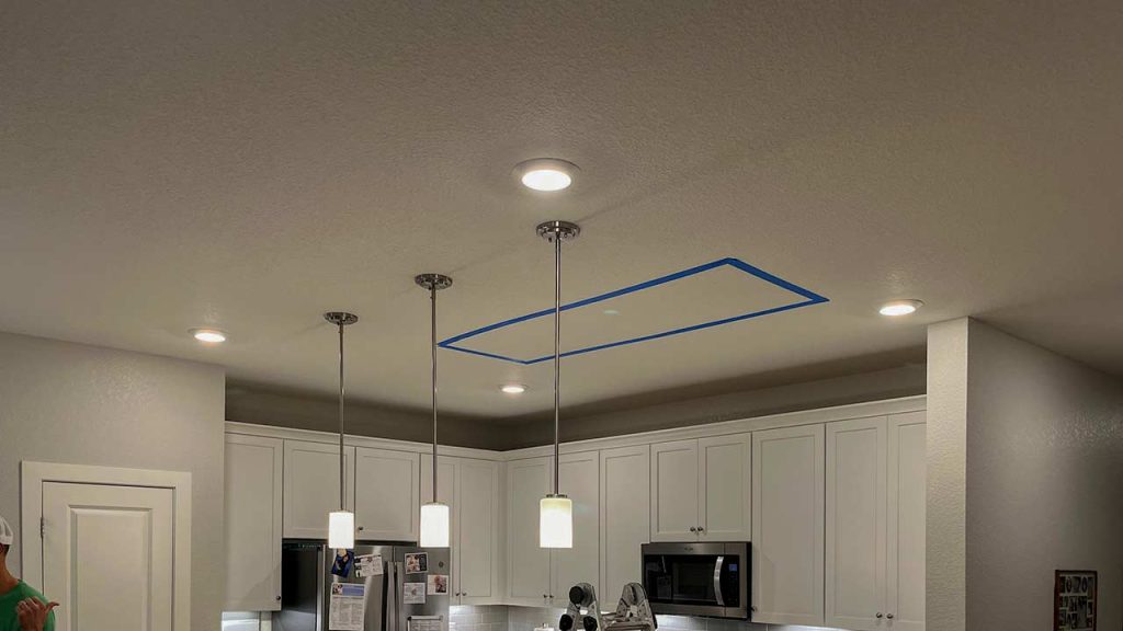 An image of the kitchen ceiling with tape outlining the portion to be cut out.