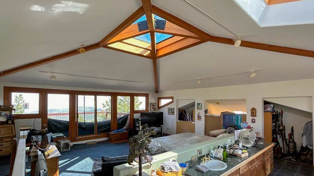 A cozy bedroom featuring a skylight above a neatly made bed, allowing natural light to fill the space. b