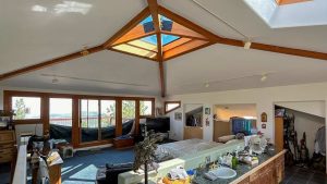 A cozy bedroom featuring a skylight above a neatly made bed, allowing natural light to fill the space. b