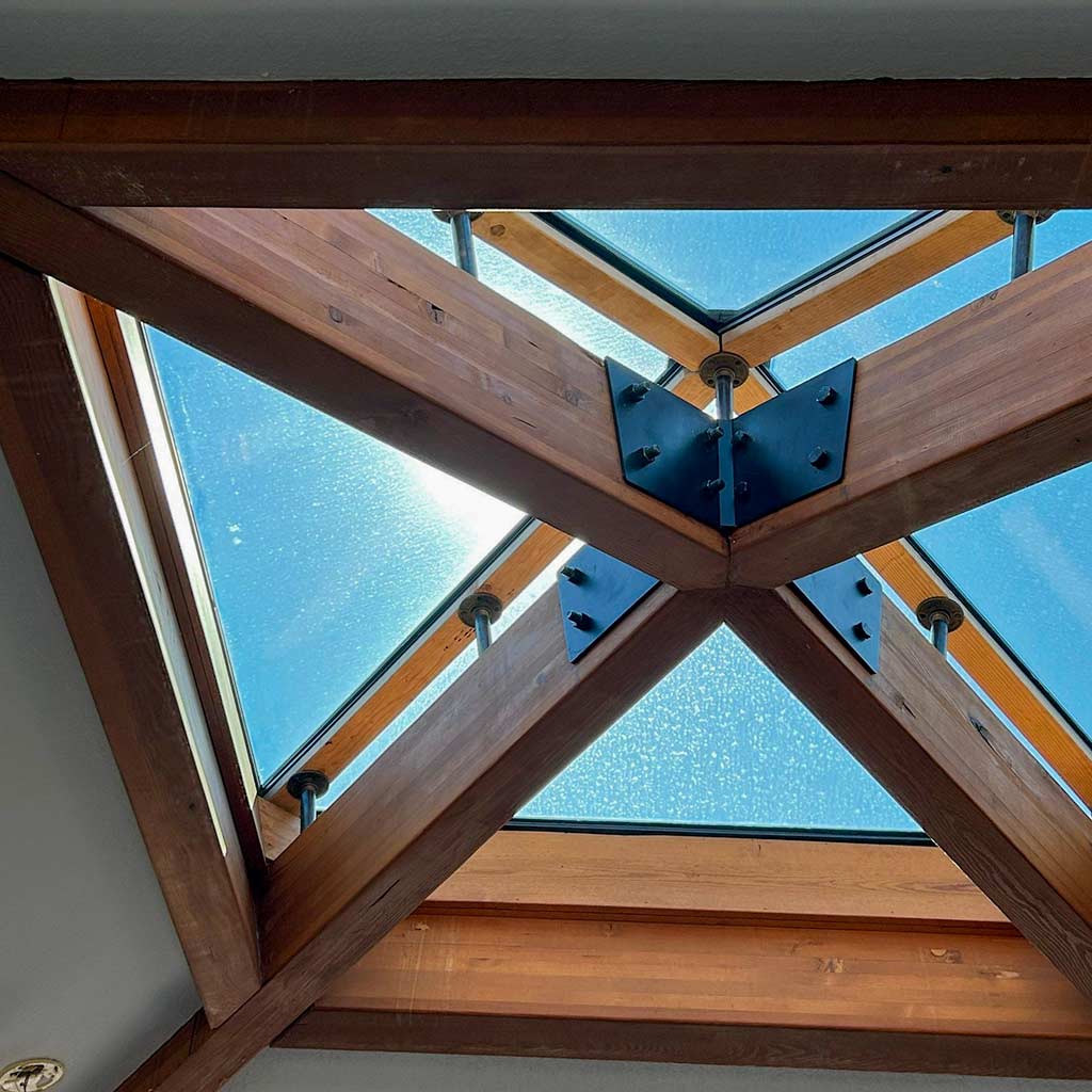 Sunlight filters through a skylight framing of wooden beams, creating a warm and inviting atmosphere.