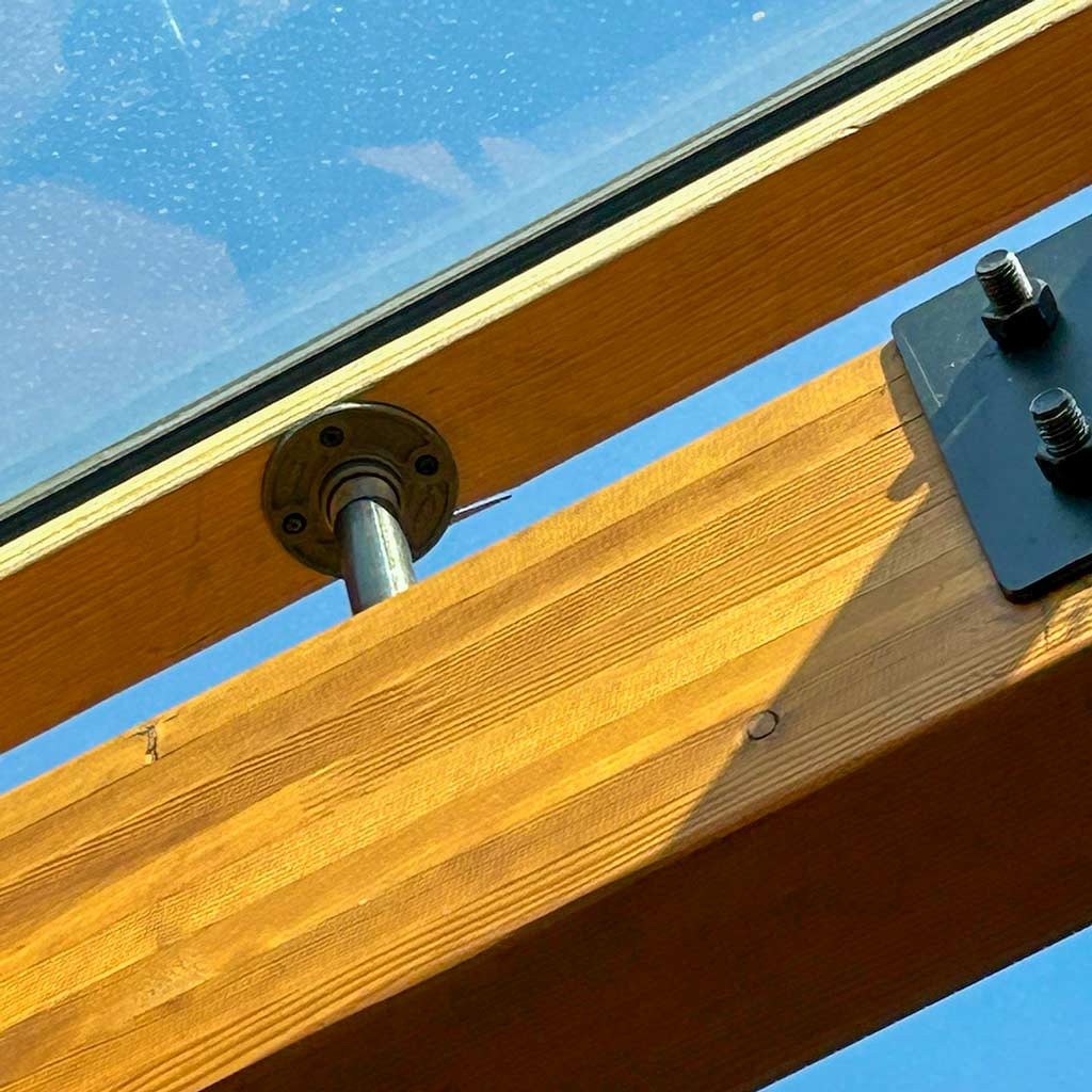 A closeup image of gas line pipe and flange holding the MADS Bar framing above the beams.