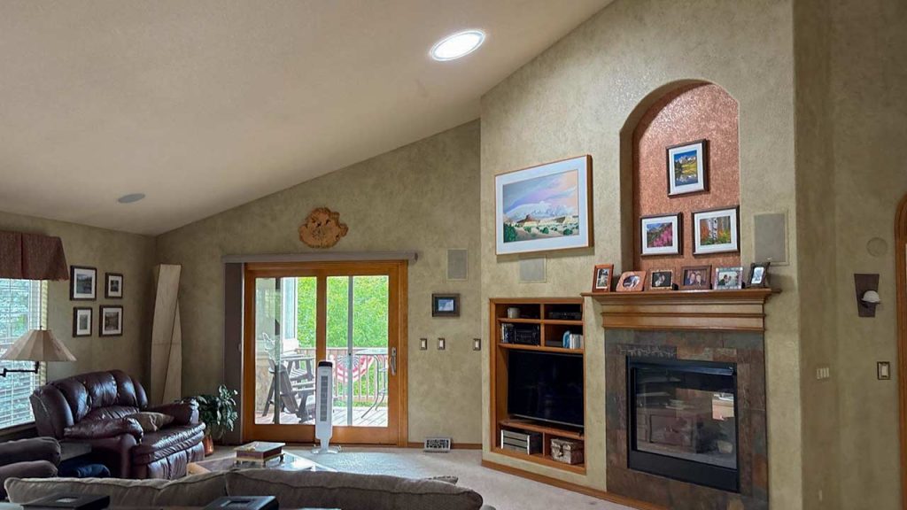 A cozy living room featuring a fireplace, television, and a VELUX Sun Tunnel installed in the ceiling for natural light.