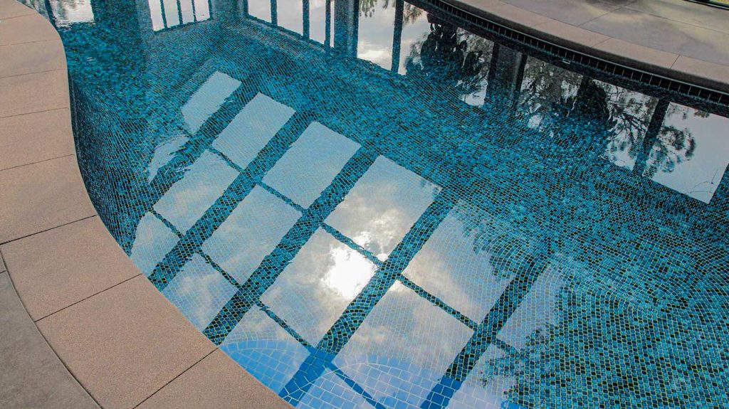 Indoor pool showcasing a mosaic base, with a reglection of the sky through the skylighy above.