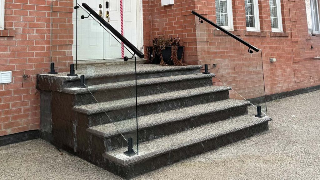 Red brick building with a white double door decorated like a gift, featuring a red bow. Stone steps with glass railings lead to the entrance.