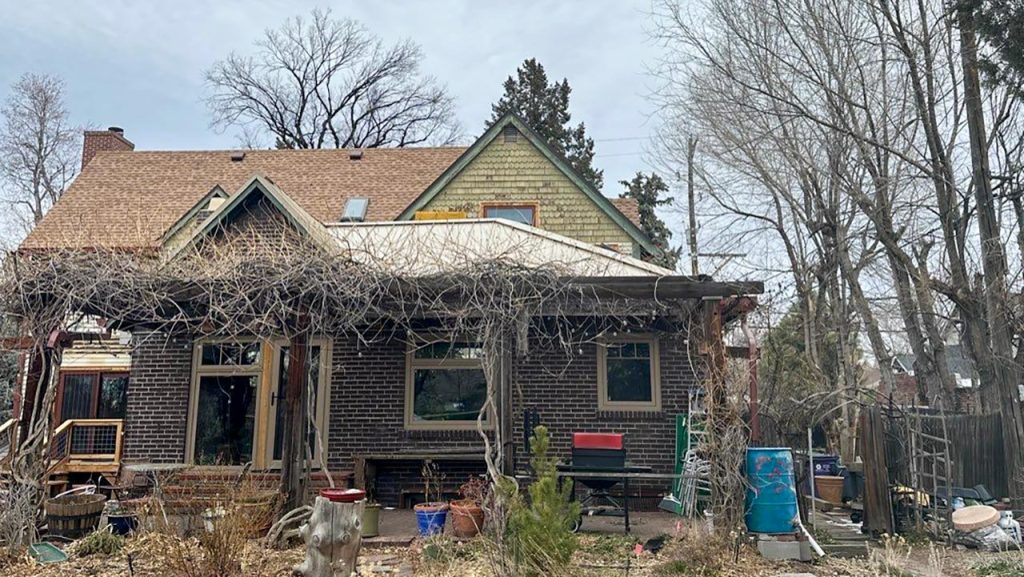 Exterior view of a residential brick house showing an asphalt shingle roof with a newly installed VELUX FCM 3030 skylight.