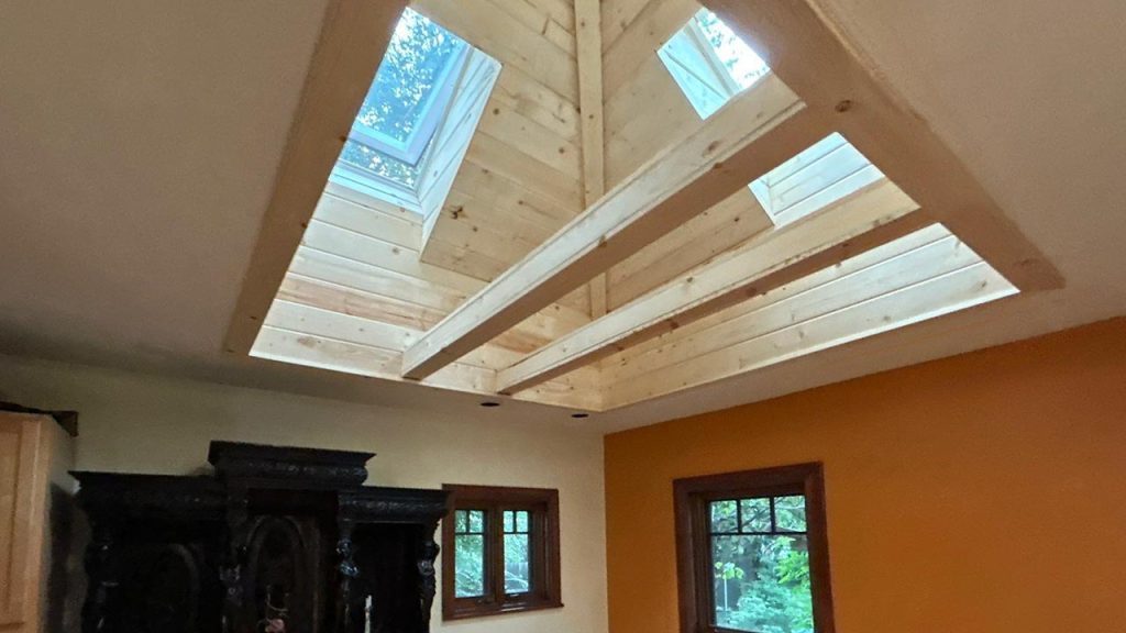 *Finished wood-plank light shaft with trim fully installed below multiple VELUX FCM 3030 skylights, flooding the room with daylight.*